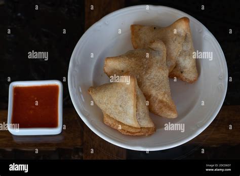 Samosas on a white plate with dipping spicy red sauce Stock Photo - Alamy