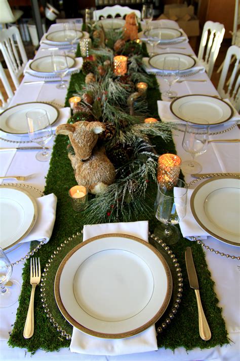 the table is set with white and gold plates, silverware, candles and ...