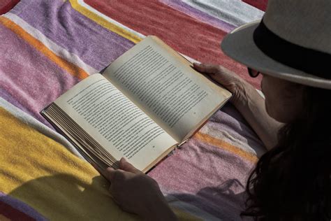 Crop woman reading book on picnic plaid · Free Stock Photo