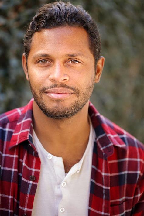 a man wearing a red and white checkered shirt looking at the camera ...