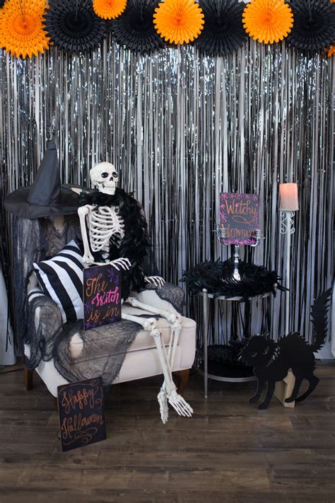 a skeleton sitting on a couch in front of a party backdrop with black and white decorations