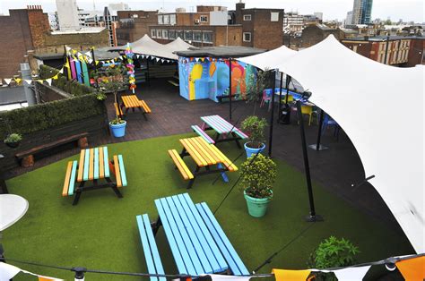 an outdoor area with benches, tables and umbrellas on top of the roof terrace