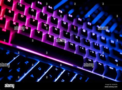 side view detail closeup of two illuminated mechanical gaming RGB keyboard on black desk on top ...