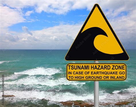 Tsunami warning and evacuation sign located on a beach. The sea and blue sky as background Stock ...