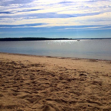 a beach with sand and water under a cloudy sky