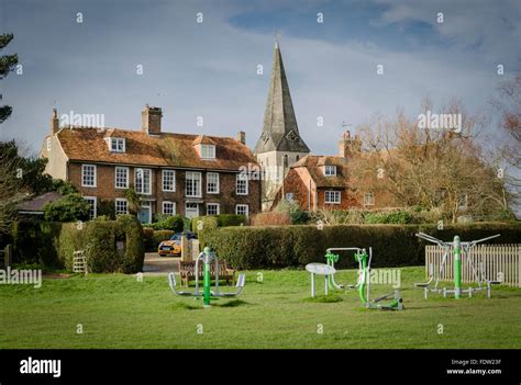 Exercise equipment on Woodchurch village green, Kent, UK, with All Saints church and brick and ...