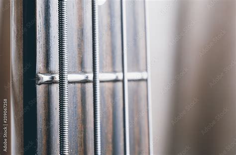 Bass guitar rosewood fretboard closeup showing string detail. Stock Photo | Adobe Stock