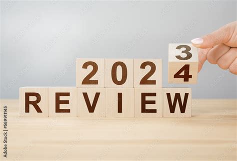 concept of review 2024. hand flips wooden cube and changes words REVIEW 2023 to REVIEW 2024. New ...