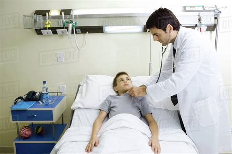 Child lying in hospital bed, doctor standing by side - Stock Photo - Dissolve