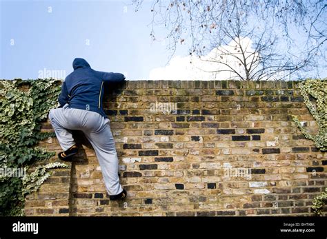 A young man climbing over a wall Stock Photo - Alamy