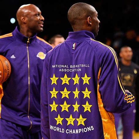 two men in purple jackets holding basketballs on a court