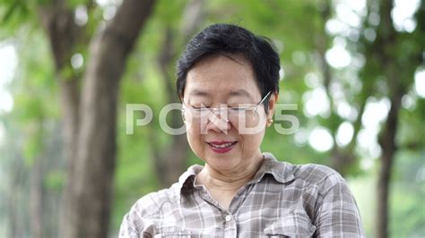 Asian senior woman sitting and reads a book in green nature background park Stock Footage,# ...