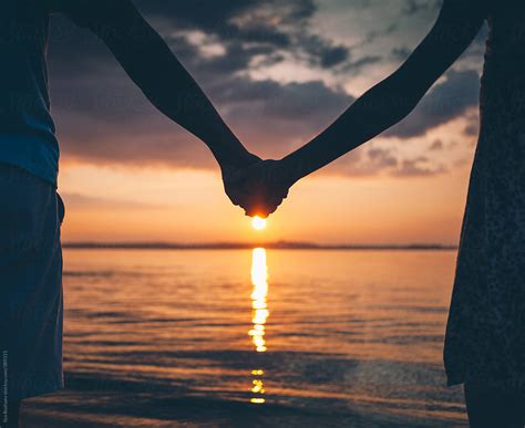 Couple Holding Hands On Nature Beach On Sunset by Ilya - Couple