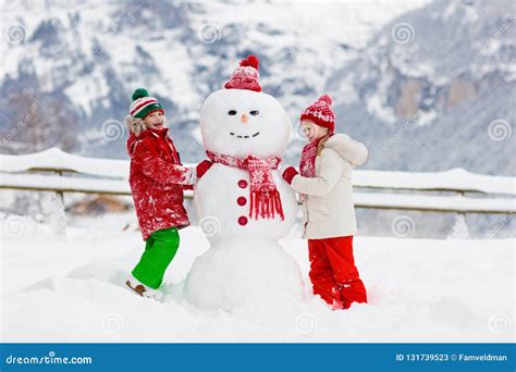 Child Building Snowman. Kids Build Snow Man. Boy and Girl Playing Outdoors on Snowy Winter Day ...