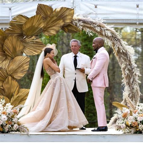 a man and woman standing next to each other in front of a wedding arch