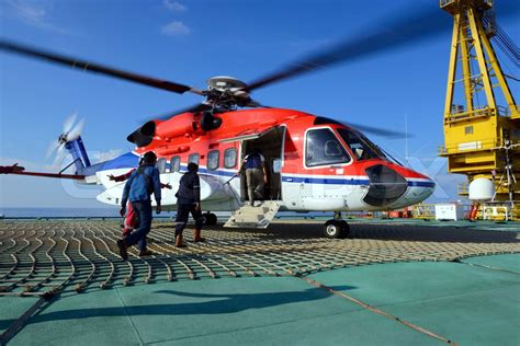 The helicopter landing officer take care passenger to embark helicopter ...