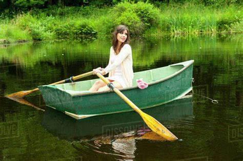 Caucasian woman rowing boat in pond - Stock Photo - Dissolve