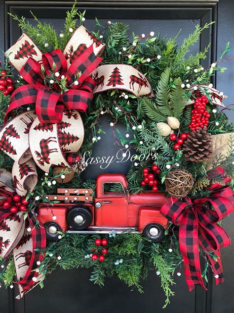 a christmas wreath with a red truck, pine cones and berries on the ...