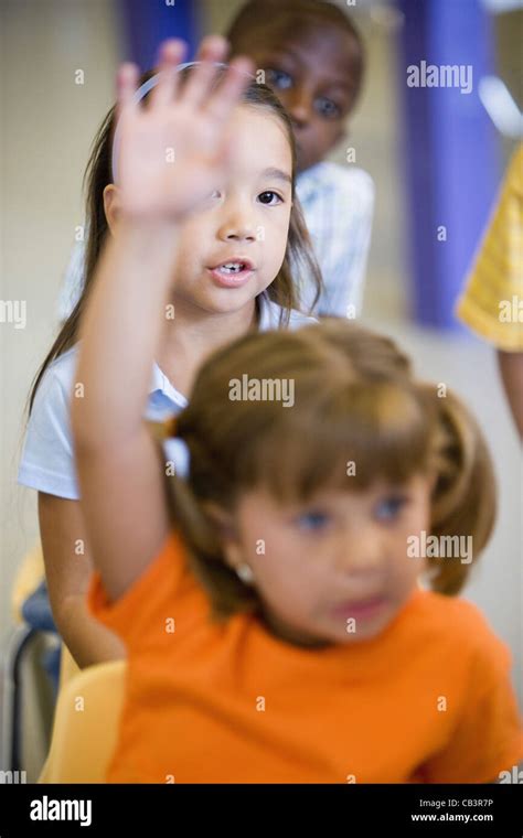 Girl raising hand in a classroom Stock Photo - Alamy