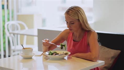 food, people and leisure concept - hungry woman eating salad for lunch with coffee at restaurant ...