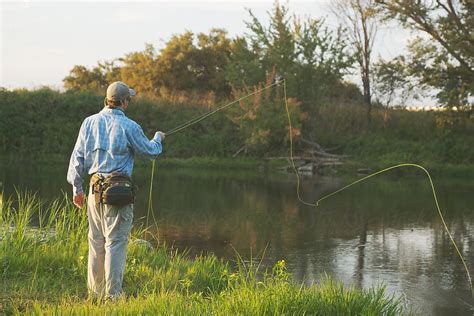 "A Young Man Fly Fishing Along A River" by Stocksy Contributor "Tana Teel" - Stocksy