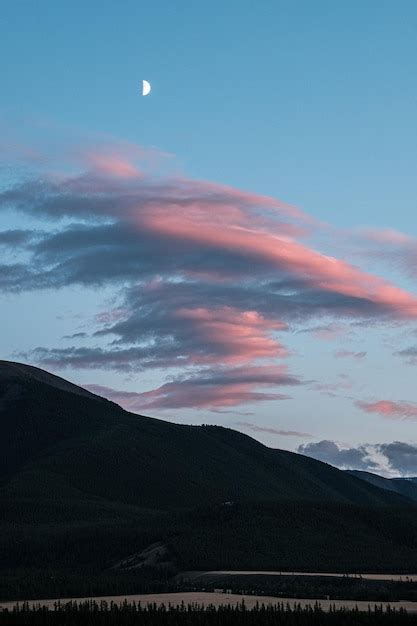 Premium Photo | View of the month above the pink clouds and the mountain during sunset