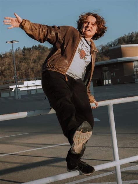 a man riding a skateboard down the side of a metal rail next to a parking lot