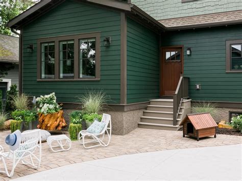 a green house with white lawn chairs in front