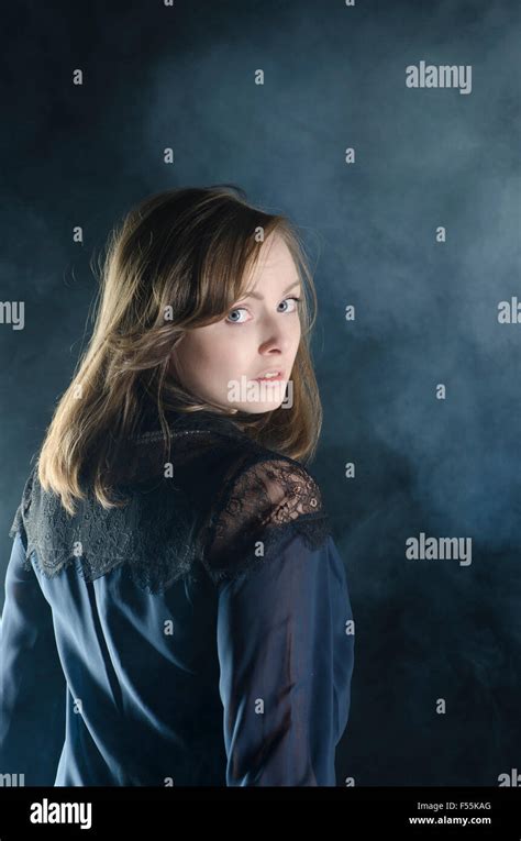 Scared young woman looking over shoulder in the dark Stock Photo - Alamy