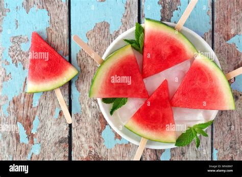 Watermelon slice popsicles on plate with a rustic blue wood background ...