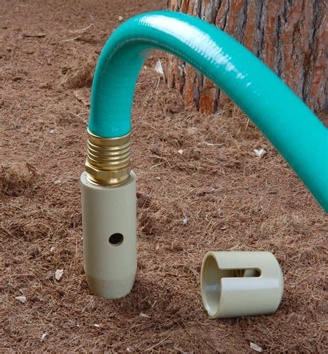 a blue hose is attached to a white plastic tube next to a brown tree trunk