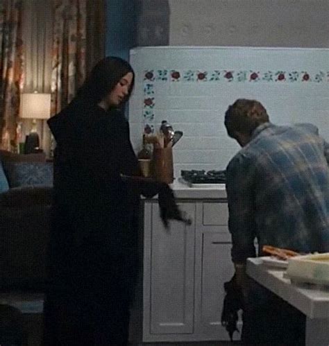 a man and woman standing in a kitchen next to a counter with food on it