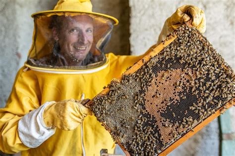 Premium Photo | Beekeeper working to collect honey smiling man holding ...