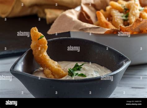 New England fried clam strips served with a bowl of tartar dipping ...