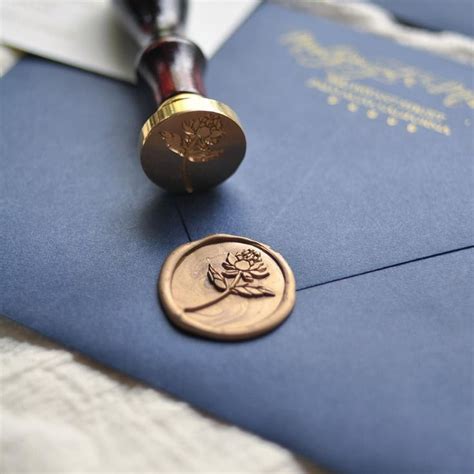 a waxed seal on top of a blue envelope with a flower stamp next to it