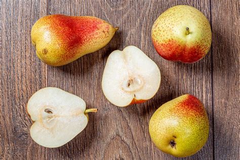 Whole ripe pears and halves on a wooden table. Top view - Creative ...