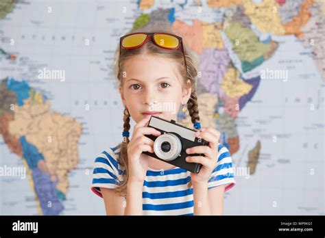 pretty little girl in striped sailor shirt and sunglasses with vintage camere in hands on world ...