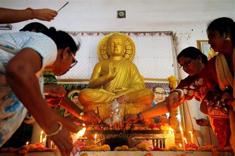 PRINT People light candles in front of a statue of Lord Buddha inside a temple on the occasion ...