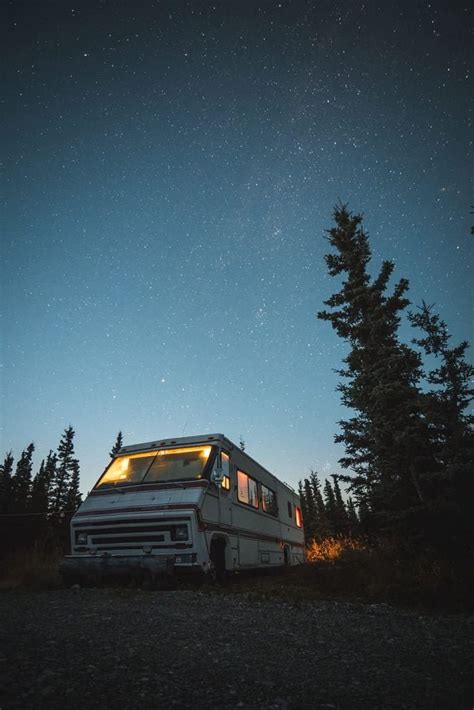 White and red RV beside trees van night sky camper star