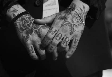 two people holding hands with tattoos on their arms and fingers, both showing the word hope