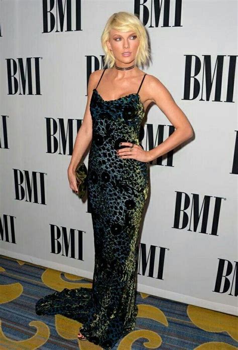 a woman in a black and green dress on the red carpet at an awards event