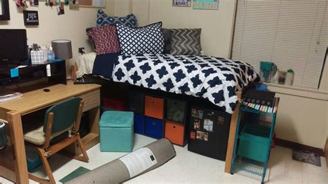 a dorm room with a bed, desk and computer on top of the dressers