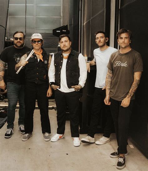 five men standing in front of a recording studio with one holding a ...