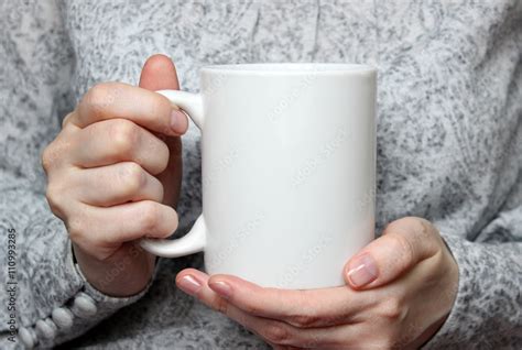 Girl is holding white cup in hands. White mug in woman's hands. Stock Photo | Adobe Stock