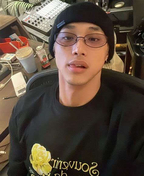 a young man wearing glasses and a beanie sitting in front of a computer ...
