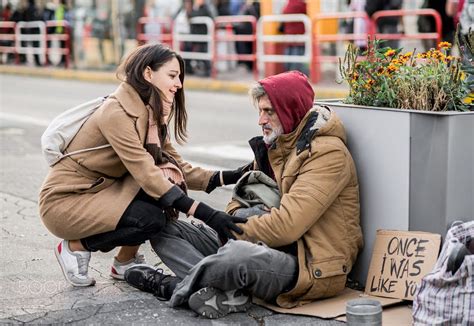 Young woman giving money to homeless beggar man sitting in city. | Man sitting, Homeless people ...