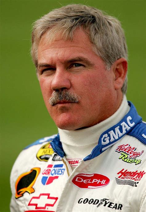 a close up of a person wearing a racing suit and moustache on his face