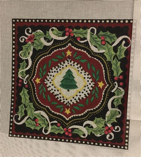 an embroidered christmas card with holly leaves and a tree in the center on a white background