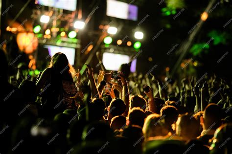 Premium Photo | Back view of excited fans cheering at music concert and taking pictures with ...