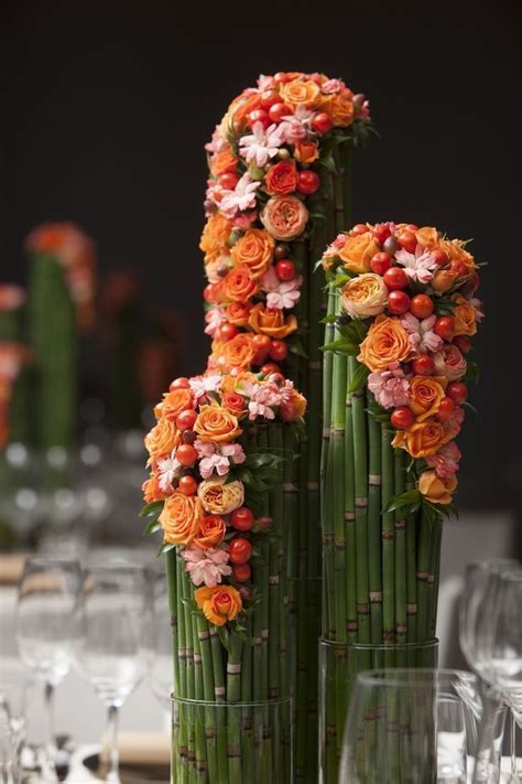 two tall bamboo vases with flowers on them are sitting on top of a table